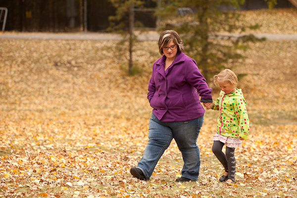 Woman and daughter walking holding hands through leaves